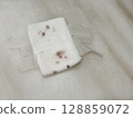 A used gauze pad with dried blood stain, placed on a table top.  128859072