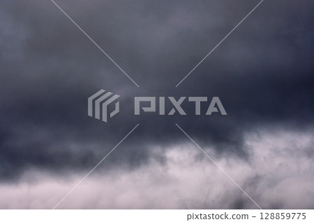 Dark storm clouds gather ominously in the sky before an anticipated rainstorm approaches the landscape Dark storm clouds gather ominously in the sky before an anticipated rainstorm approaches the landscape 128859775
