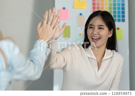 Creative Graphic Designer Collaborating in Modern Office with Color Samples and Design Tools 128859971