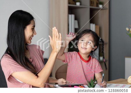 Joyful Child Engaged in Learning with Parent, Celebrating Success and Education at Home in a Supportive Environment 128860058