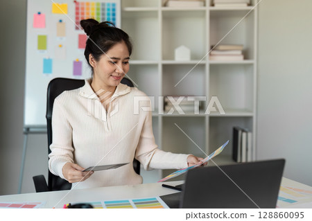 Creative Designer Working on Innovative Project in Modern Office with Color Swatches and Laptop 128860095