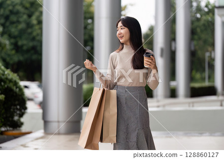 Excited Shopper Enjoying Black Friday Deals with Shopping Bags and Coffee in Modern Urban Setting Excited Shopper Enjoying Black Friday Deals with Shopping Bags and Coffee in Modern Urban Setting 128860127