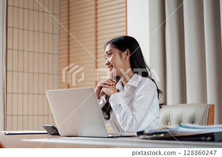 Professional Businesswoman Working at Desk with Laptop in Modern Office Environment 128860247