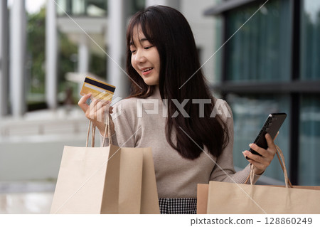 Excited Shopper Holding Credit Card and Smartphone During Black Friday Sale Outside Modern Shopping Mall Excited Shopper Holding Credit Card and Smartphone During Black Friday Sale Outside Modern Shopping Mall 128860249