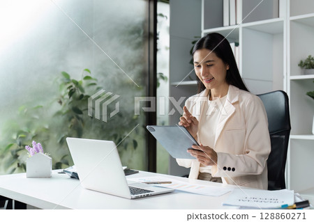 Professional Woman in Modern Office Using Tablet and Laptop for working in office 128860271