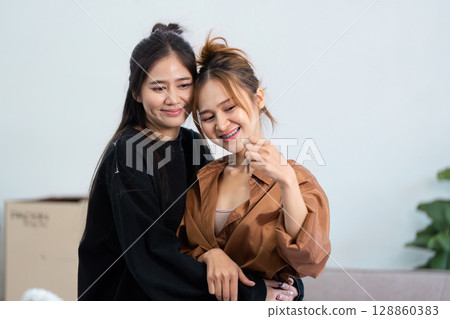 Happy Couple lesbian lgbt Embracing in New Home with Moving Boxes and Cozy Interior Background 128860383