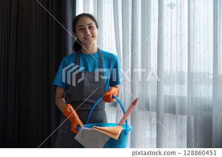 Professional Housekeeper with Cleaning Supplies in Modern Home Setting 128860451