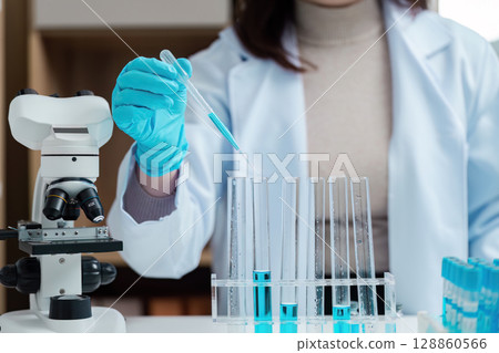 Scientist Conducting Experiment in Modern Laboratory with Test Tubes and Microscope 128860566