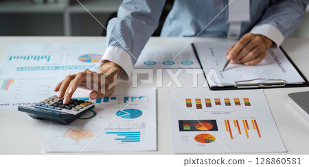 Business Professional analysis Financial Data with Chart and Calculator in Modern Office Setting 128860581