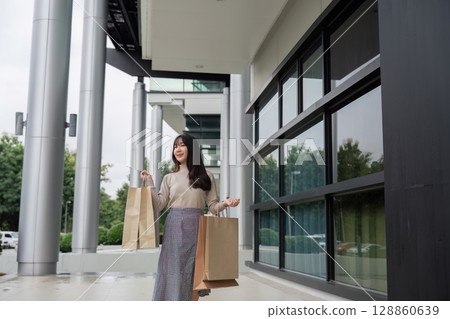 Excited Shopper Holding Bags on Black Friday Outside Modern Shopping Mall Excited Shopper Holding Bags on Black Friday Outside Modern Shopping Mall 128860639