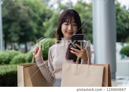 Excited Shopper Enjoying Black Friday Deals with Shopping Bags and Smartphone Outdoors 128860667