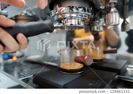 Barista Preparing Fresh Espresso with Professional Coffee Machine in Modern Cafe 128861332