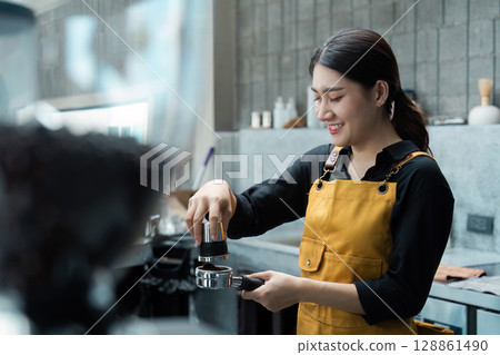 Barista in Yellow Apron Preparing Espresso in Modern Coffee Shop 128861490