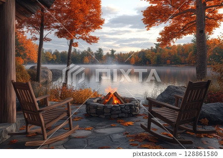 A cozy scene with a fire pit and two wooden rocking chairs by a lake 128861580