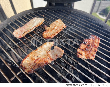 Bone-in rib eye steak seasoned with herbs and spices grilling ver a hot BBQ fire in a view from above with copy space 128861952