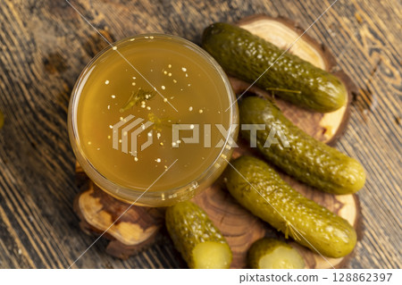 pickled cucumbers marinated and pickled ripe cucumbers next to a glass, poured pickle with spices and whole crispy cucumbers on a board, close up pickled cucumbers marinated and pickled ripe cucumbers next to a glass, poured pickle with spices and whole crispy cucumbers on a board, close up 128862397