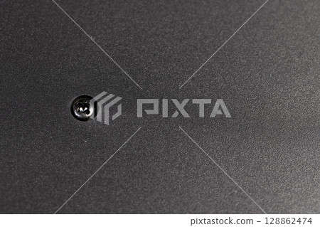 A bolt is screwed into the plastic to connect the different parts of the object. details of a part of an object made of black plastic 128862474