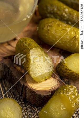 pickled marinated and pickled cucumbers next to a glass, poured pickle with spices and whole crispy cucumbers on a board 128862486