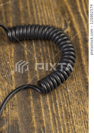 a cable twisted in the shape of a spring for equipment , an old black cable in a rubber braid for connecting different devices 128862574