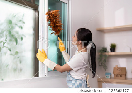 Window Cleaning. Woman dusting window with duster in bright room. 128862577