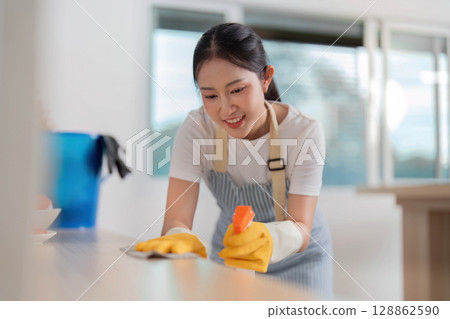 Home Cleaning. Happy woman wiping a surface with a cloth in a clean kitchen. Home Cleaning. Happy woman wiping a surface with a cloth in a clean kitchen. 128862590
