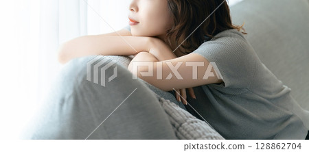 Woman relaxing on sofa by the window Woman relaxing on sofa by the window 128862704