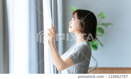 Woman opening curtain Woman opening curtain 128862707