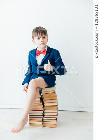 Boy sitting on stacks of educational books 128865131