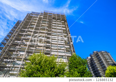 Yokohama cityscape in Japan: Summer sky spreads out... Repairs and inspections of apartment buildings, scaffolding, protective nets, satellite antennas... 128865132