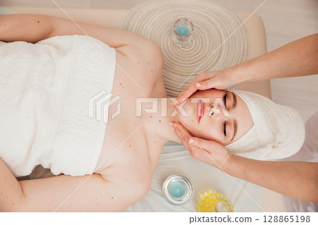 Massage therapist doing medical facial massage to woman 128865198