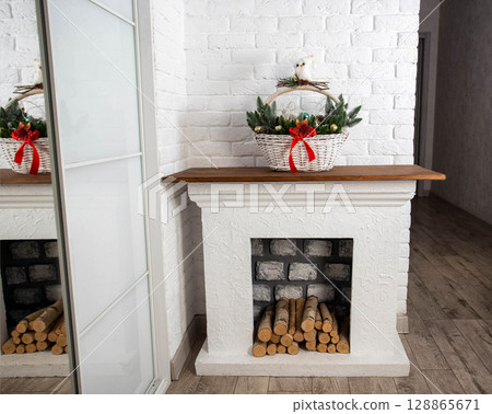 Handmade fireplace with logs and Christmas basket on top, close-up. Copy space for text Handmade fireplace with logs and Christmas basket on top, close-up. Copy space for text 128865671