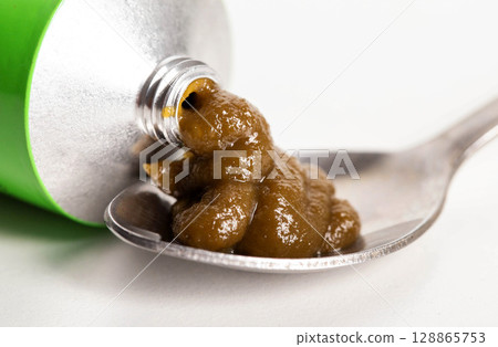 Medicinal urological paste on herbs in a spoon, close-up. Treatment of cystitis and urethritis, macro 128865753