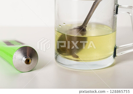 Urological paste on herbs against the background of a glass of water. Treatment of infectious inflammatory diseases of the urinary system, close-up 128865755