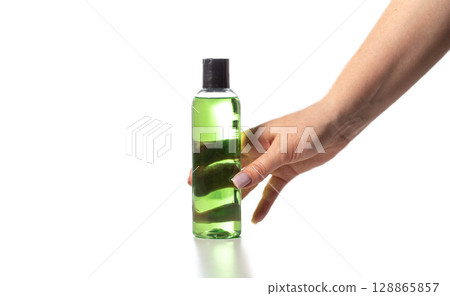 Green liquid in hand concentrate in bottle on white background, isolate. 128865857