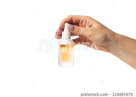 Yellow bottle in hand with oil for hair ends in hand on white background, isolate, close-up 128865878