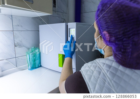 A Medical Professional in Personal Protective Equipment Operating a High-Tech Freezer in a Clean Lab Environment While Interior Design Showcases Modern Materials and Colors A Medical Professional in Personal Protective Equipment Operating a High-Tech Freezer in a Clean Lab Environment While Interior Design Showcases Modern Materials and Colors 128866053