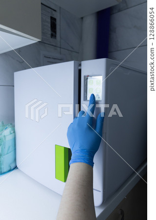 A Professional's Gloved Hand Interacting with a Medical Equipment Display: Emphasizing Hygiene and Technology in Clinical Settings A Professional's Gloved Hand Interacting with a Medical Equipment Display: Emphasizing Hygiene and Technology in Clinical Settings 128866054