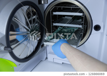 A Medical Professional Operating a Sterilizer with Gloved Hands for Effective Cleaning and Safety in Healthcare Environments and Laboratory Settings A Medical Professional Operating a Sterilizer with Gloved Hands for Effective Cleaning and Safety in Healthcare Environments and Laboratory Settings 128866069