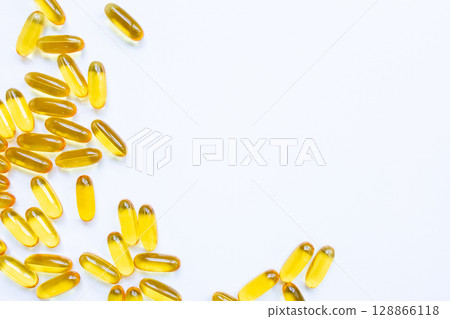 Yellow oil capsules scattered on white surface in minimalist style 128866118