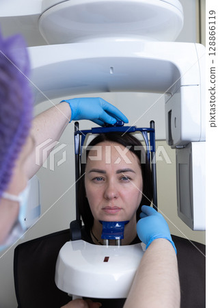 Patient Preparing for a Dental Imaging Procedure in a Professional Clinic Setting with Modern Medical Equipment for Accurate Diagnostics and Treatment Planning 128866119