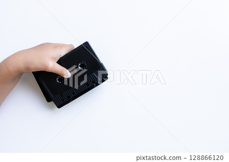 Hand holding black cassette tape on white background 128866120