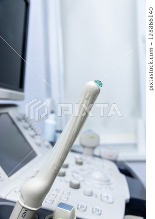 Close-Up of an Ultrasound Probe on a Medical Console Amidst a Clean and Modern Medical Environment with Equipment Ready for Efficient Patient Care and Diagnostics Close-Up of an Ultrasound Probe on a Medical Console Amidst a Clean and Modern Medical Environment with Equipment Ready for Efficient Patient Care and Diagnostics 128866140