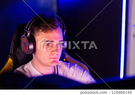 cyber player emotionally plays real-time strategy game, facial expressions. Guy is participating in Esports event at LAN cafe. Professional gamer playing multiplayer shooter on desktop cyber player emotionally plays real-time strategy game, facial expressions. Guy is participating in Esports event at LAN cafe. Professional gamer playing multiplayer shooter on desktop 128866148