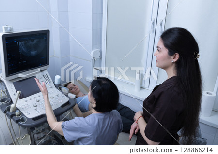 Medical Ultrasound Examination in Progress with Caring Health Professionals and a Patient Undergoing a Diagnostic Procedure in a Modern Healthcare Setting 128866214