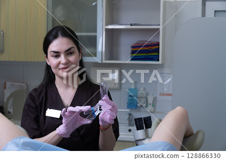 A dental professional wearing gloves prepares instruments for a patient in a modern clinical setting, showcasing the importance of hygiene and patient care in dentistry practices. 128866330