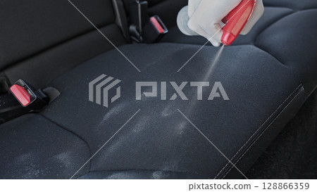 Application of a cleaning chemical on the upholstery of the seat. Concept advertisement of professional car dry cleaning service and professional car chemistry. Copy space. Backdrop. Application of a cleaning chemical on the upholstery of the seat. Concept advertisement of professional car dry cleaning service and professional car chemistry. Copy space. Backdrop. 128866359