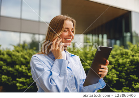 Young woman is engaged in a meaningful conversation while using her tablet device outdoors Young woman is engaged in a meaningful conversation while using her tablet device outdoors 128866406