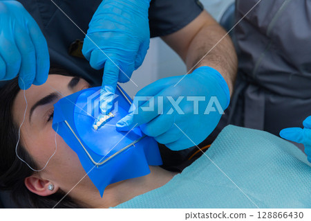 Dental Professionals Perform a Precise Procedure Utilizing Advanced Tools for Oral Care with Blue Gloves and an Innovative System for Effective Treatment Dental Professionals Perform a Precise Procedure Utilizing Advanced Tools for Oral Care with Blue Gloves and an Innovative System for Effective Treatment 128866430