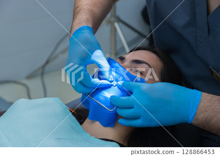 Professional Dental Procedure in Progress: Hygienist Applying Rubber Dam on Patient for Improved Oral Health Treatment and Comfort During Procedure Professional Dental Procedure in Progress: Hygienist Applying Rubber Dam on Patient for Improved Oral Health Treatment and Comfort During Procedure 128866453