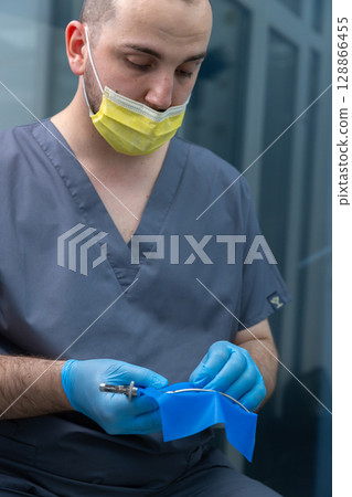 Healthcare Professional Preparing for a Procedure while Adhering to Safety Protocols in a Medical Environment Featuring a Surgical Blue Drape and Protective Gear Healthcare Professional Preparing for a Procedure while Adhering to Safety Protocols in a Medical Environment Featuring a Surgical Blue Drape and Protective Gear 128866455